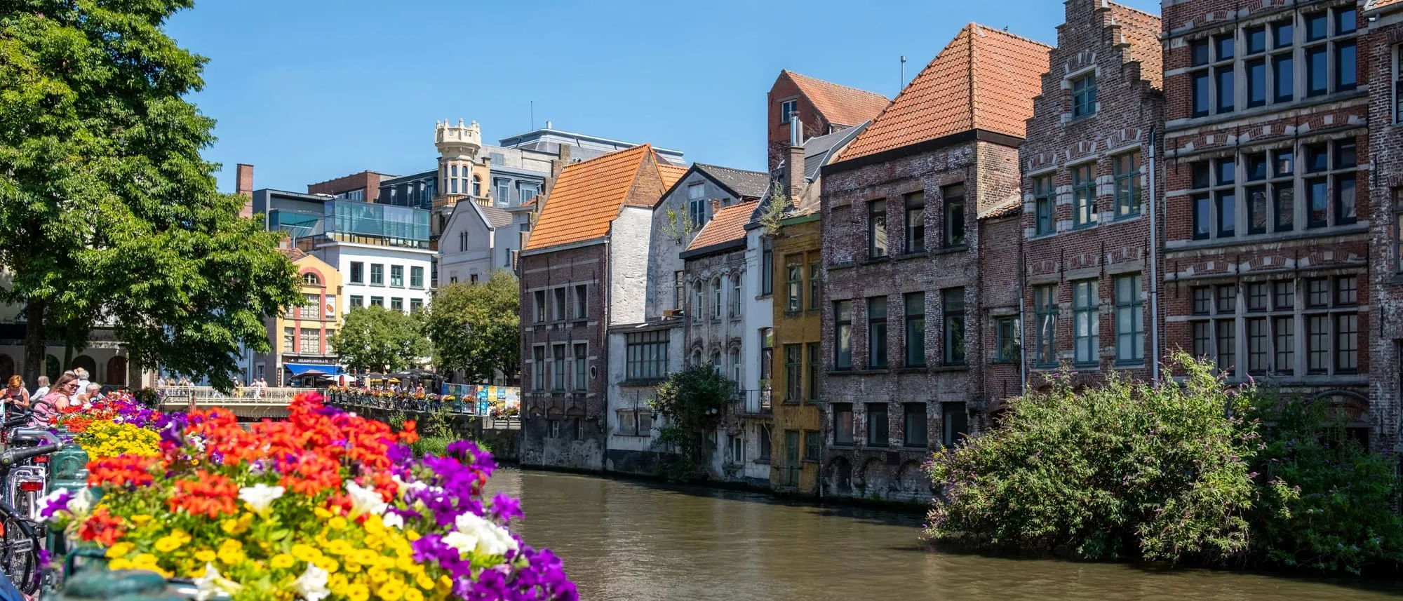 Historische gevels langs de Leie in Gent in de lente, met bloembakken op de voorgrond