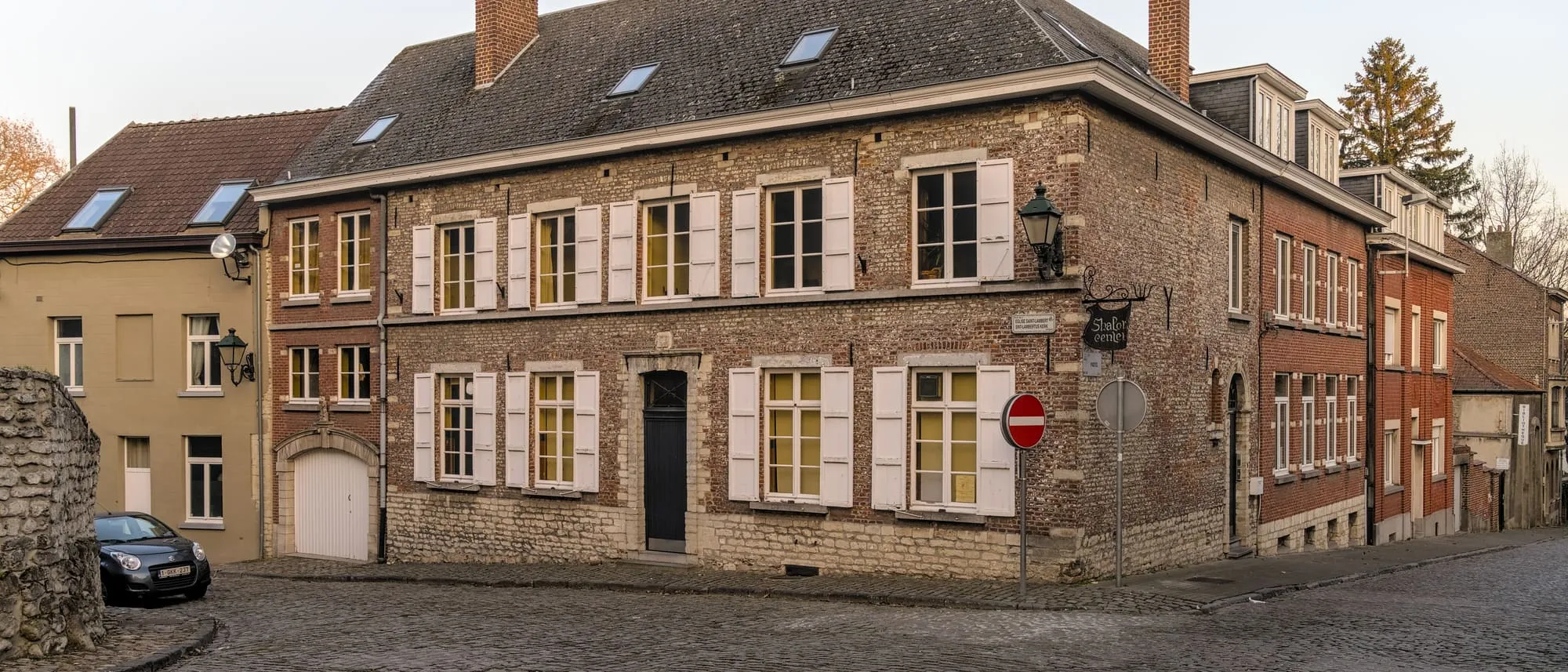 L'ancienne maison communale de Woluwe-Saint-Lambert, façade en briques et volets, au soleil couchant